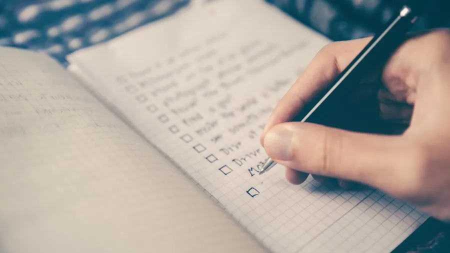 A hand ticking items on a checklist in a notebook