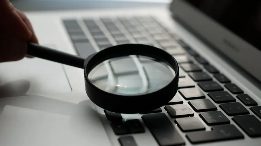 A magnifying glass over a laptop keyboard, representing search